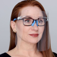 Woman with red hair wearing a facial protective shield with prescription glasses underneath