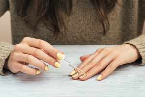 A stock image of person applying yellow nail polish