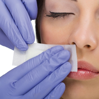 An image of AHP member lip waxing service. An esthetician applies a lip wax strip on their client.