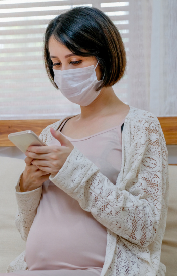 An image of pregnant woman with face mask on abdomen