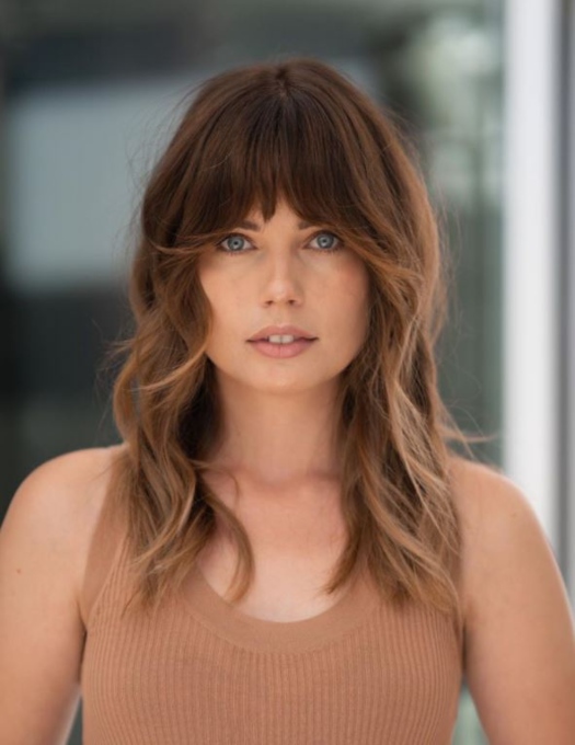 A model shows off her new modern shag haircut featuring face framing bangs.