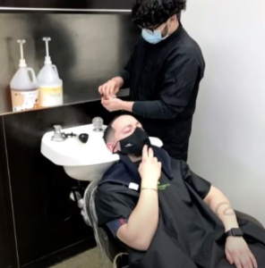 A stock image of male hairstylist shampooing male client