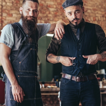 Two barbers stand together in their barber shop in honor of mental health awareness month