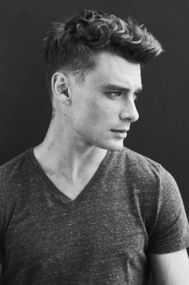 Black and white photo of a man in gray t-shirt with textured haircut