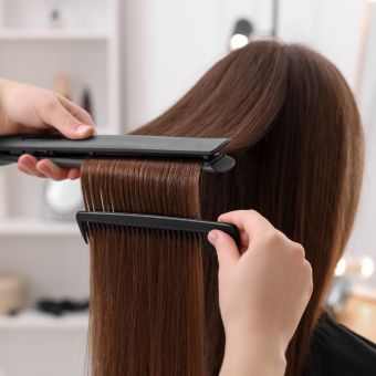 Long brown hair being straightened with a flat iron