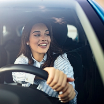Smiling woman driving with hands on the steerling wheel looking out the window
