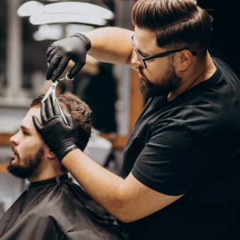 Hair professional cutting a male client's hair with shears