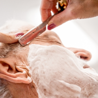Man receiving a straight razor shave by a barber