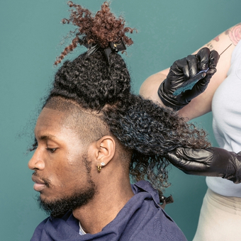 Black man with coily hair receiving a color hair service from a cosmetologist