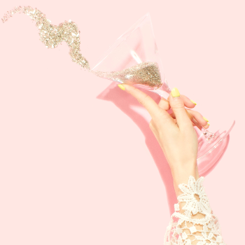 An image of hand holding martini glass filled with glitter 