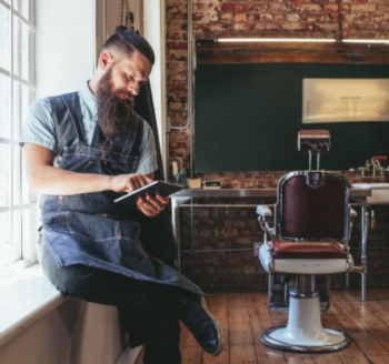 A stock image of male hairstylist using tablet