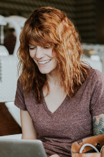A stock image of woman on laptop with red hair smiling