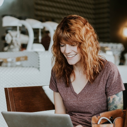 A stock image of woman on laptop with red hair smiling