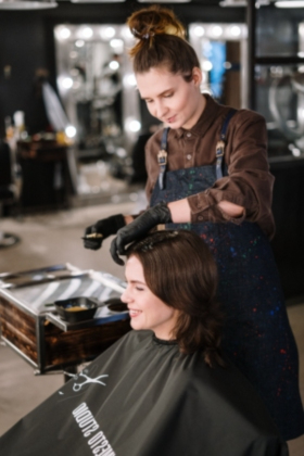 A stock image of female hairstylist provding color service to client