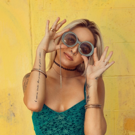 A stock image of woman wearing sunglasses on yellow background