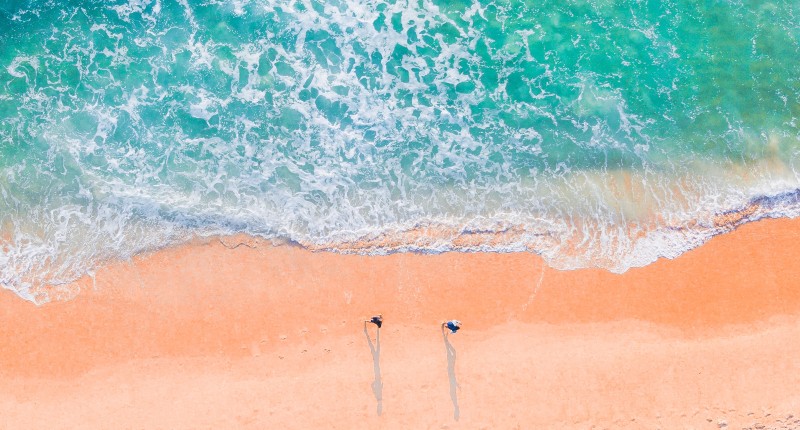 An image of two people on a beach looking down