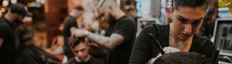 A professional barber works on a client in a well-ventilated salon.