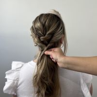 Creating a low ponytail at the base of the hair.