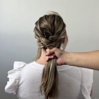 Creating a low ponytail at the base of the hair.