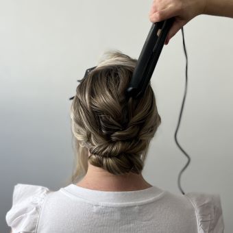 Using a hair straightener to compress base sections and create volume and dimension.