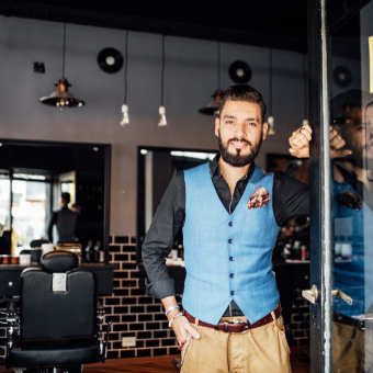 confident barber standing at the entrance of his shop