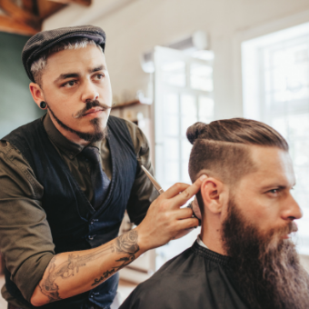 bearded man getting haircut by barber