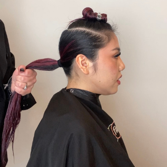 Profile view of a client with the back of their hair pulled into a ponytail to start an octopus haircut.