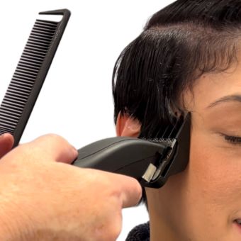 A hairstylist uses clippers on their client to create an undercut.