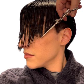 A hairstylist lines up their client’s bangs with the cheekbone to create a V shape.