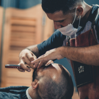 Barber shaves client's face