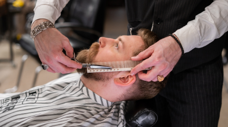 Barber trim client's beard with scissors