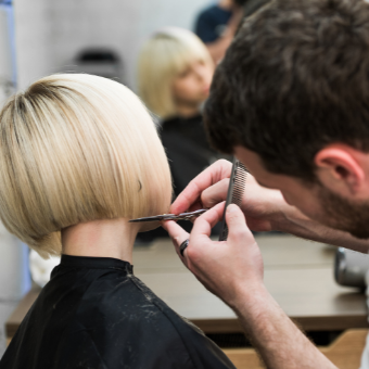 Hairdresser trims woman's blond bob