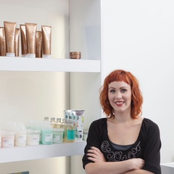 Woman stands next to a shelf with hair product