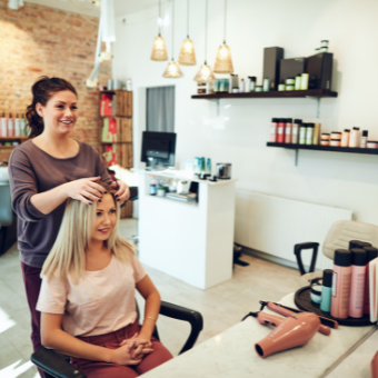 Hairdresser styling client's hair at her hair station