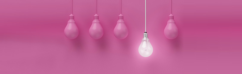 Light bulb hanging from ceiling in a salon with a pink background.