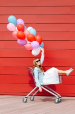 girl sitting in a grocery cart with balloons