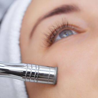 Cosmetologist performing microdermabrasion on client