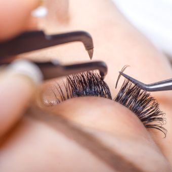 Professional using tools to separate lashes and apply eyelash extensions