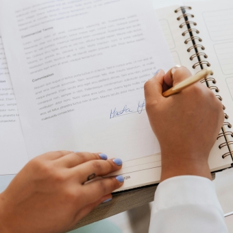 Woman with polished blue nails signing a contract with gold pen